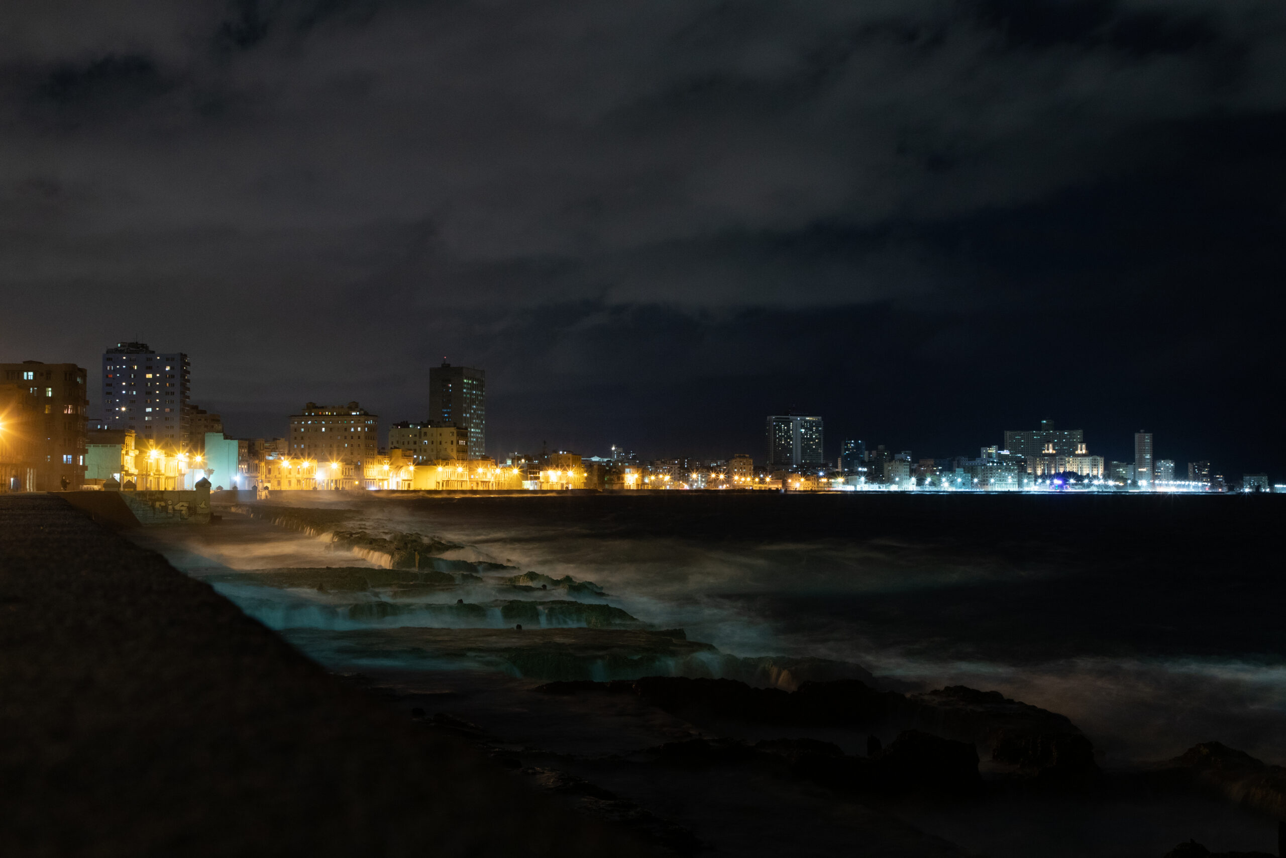 Evening scene of Havana’s Malecón on 21 January 2019, captured with a 2.5-second exposure. The long exposure smooths the crashing waves along the seawall, while city lights illuminate the coastal buildings under a cloudy night sky, creating a tranquil yet dramatic atmosphere.